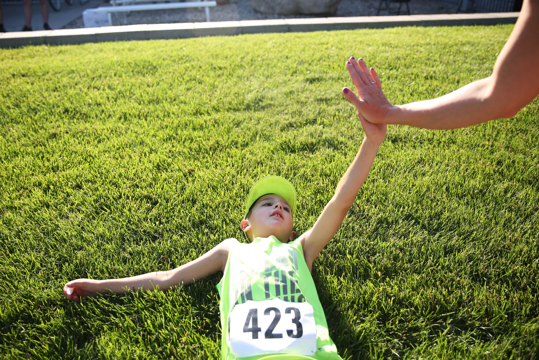 Trajen Mader, 8, sprawls on the ground after completing the 5K run